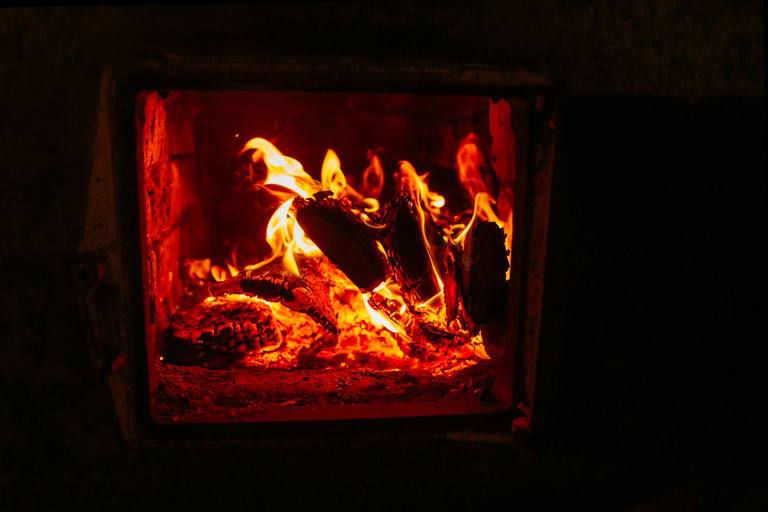 Logs burning brightly inside a dark fireplace opening with a metal frame.